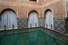 an indoor swimming pool in the middle of a building with decorative tile work on it