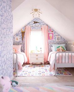 two beds in a room with pink and blue wallpaper on the walls next to each other