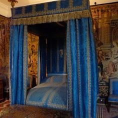 an ornate bedroom with blue bedding and paintings on the walls