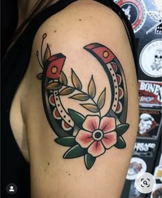 a woman's arm with a flower and horseshoe tattoo design on her left shoulder