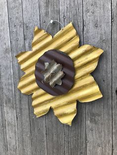 a wooden sunflower decoration hanging on the side of a building with wood planks