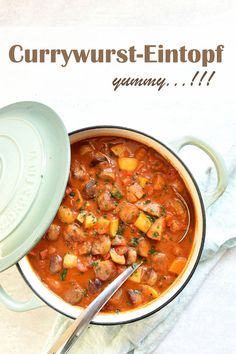 a bowl filled with stew next to a spoon on top of a white tablecloth