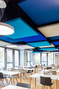 an empty restaurant with tables and chairs in front of large windows that have bright blue skylights hanging from the ceiling