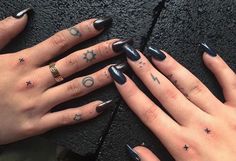 two hands with black and white nail polishes on their fingers, one has stars