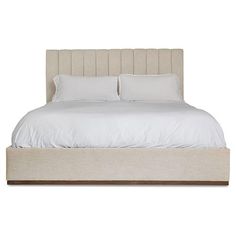 a bed with white linens and pillows on top of the headboard is shown