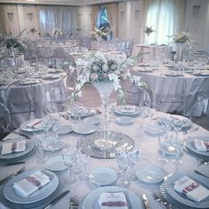 the table is set with silver and white plates, napkins, and centerpieces