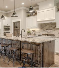 a large kitchen with white cabinets and marble counter tops, along with bar stools