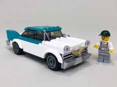 a toy car with a lego man next to it on a white surface and gray background