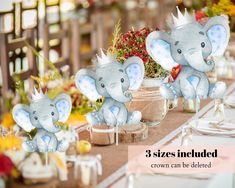 three stuffed elephants sitting on top of a table next to plates and cups with flowers in them