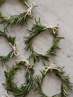 four wreaths tied with twine and rope on a marble countertop in front of a red frame