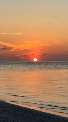 the sun is setting over the water on the beach