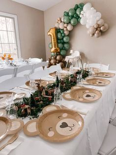 a table set up for a party with plates and balloons in the shape of animals