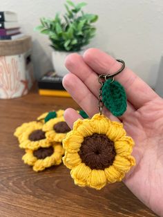 a hand holding two crocheted sunflower key chains