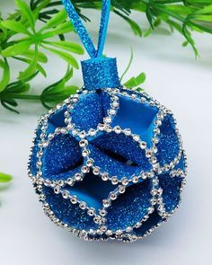 a blue ornament sitting on top of a green plant covered in crystal stones