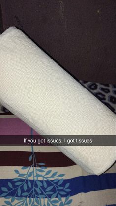 a roll of toilet paper sitting on top of a bed next to a pillow that says, if you got issues, i got tissues