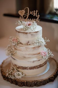 a white wedding cake sitting on top of a wooden slice with the word just married written on it