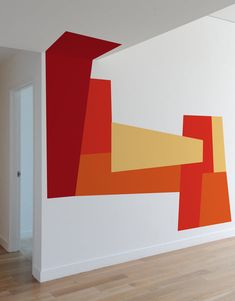 an abstract painting on the side of a wall next to a door and hardwood floor