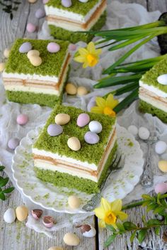 four pieces of green cake on a plate with flowers and eggs around the edges,