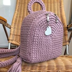 a purple handbag sitting on top of a chair next to a wicker chair