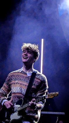 a young man playing an electric guitar on stage