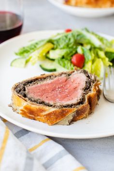 a white plate topped with meat next to a salad