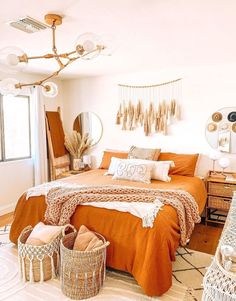 a bedroom with an orange comforter and white bedding in the corner, two wicker baskets on the floor