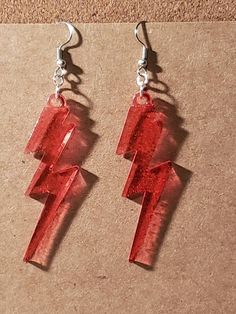 These fun lightning bolt earrings are handmade with resin and nickel free earring hooks. The red color adds a fun pop to any outfit. They are 3 inch long by 1/2 inch wide. They are very light weight and easy for all day wear. Handmade with love and the hopes that they will be loved for years to come.  Part of the proceeds from this sale will go towards helping those in need in the Pacific Northwest Communities.  Thank you for your support in advance! Bolt Earrings, Red Lightning, Lightning Bolt Earrings, Crochet Cable, Neon Red, Nickel Free Earrings, Red Jewelry, Handmade Hat, The Pacific Northwest