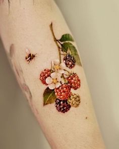 a woman's arm with flowers and berries on it