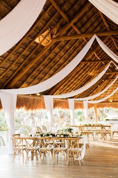 an indoor wedding venue with white draping and wooden tables set up for the reception