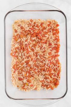 rice and tomato sauce in a square glass dish on a white tablecloth, top view from above