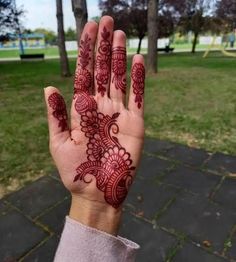 a woman's hand with henna on it in the middle of a park