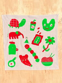 a white towel with green and red designs on it, sitting on top of a wooden table