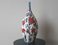 a white and blue vase sitting on top of a black table next to a gray wall