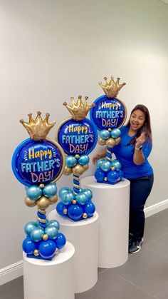 a woman standing next to some balloons with blue and gold decorations on top of them