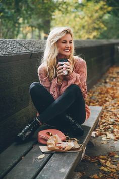 a woman sitting on a bench holding a cell phone and looking at the camera with her legs crossed