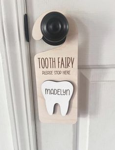 a tooth shaped door hanger on a white door with the words, tooth fairy please stop here madelyn