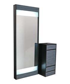 an illuminated mirror sitting next to a black dresser and cabinet on a white background with light coming from the top