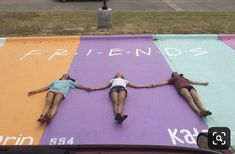 two people laying on top of a multi colored parking lot with the word friends painted on it