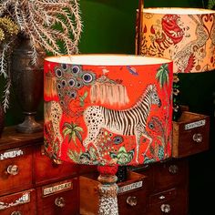 two lamps are sitting on top of dressers in a room with green walls and wooden drawers