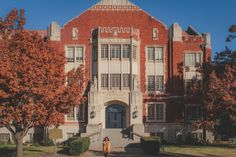 a woman standing in front of a building with trees around her and the door open