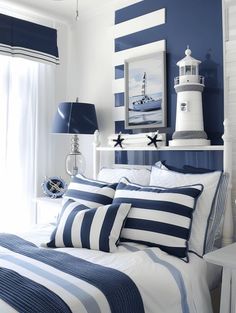 a bed with blue and white striped pillows in a bedroom next to a lighthouse on the wall