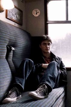 a man sitting on a train seat with his feet up against the window sill