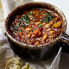 a bowl filled with beans and bread on top of a table