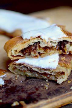 a pastry with white frosting on it sitting on top of a wooden cutting board