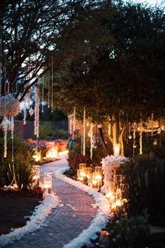 a pathway with candles and flowers on the sides is lit up by hanging chandeliers