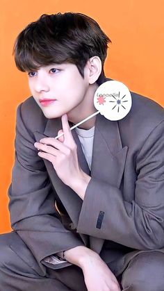 a young man in a suit and tie holding a pin with an arrow on it