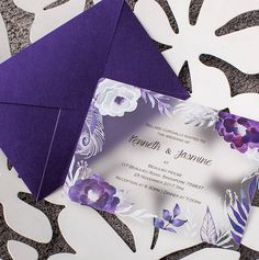 an elegant purple and white wedding card with flowers on the inside is displayed in front of a paper envelope