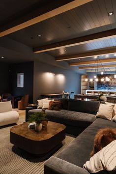 a living room filled with lots of furniture next to a bar and dining area in the background