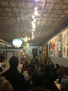 a group of people sitting in a room with pictures on the wall and ceiling above them