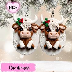 two brown and white cows with bows on their heads are hanging from a christmas tree